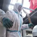 Worker in protective gear performing emergency repair on industrial reaction kettle