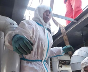 The image depicts a worker from Junyuan Petroleum Group wearing protective clothing and gloves while carrying out emergency maintenance on a large industrial reaction kettle. Surrounded by complex piping and equipment, the technician works with precision to resolve a critical agitator bearing fault. This urgent repair highlights the team’s rapid response capability, technical expertise, and commitment to safeguarding safe production of pentane, hexane, and heptane products.